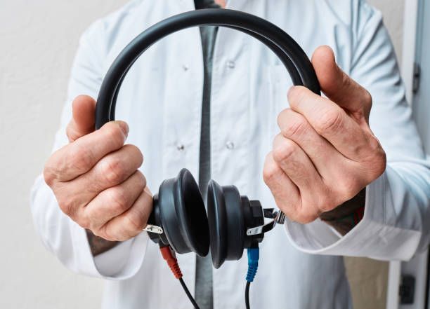 A doctor is holding a pair of headphones in his hands.