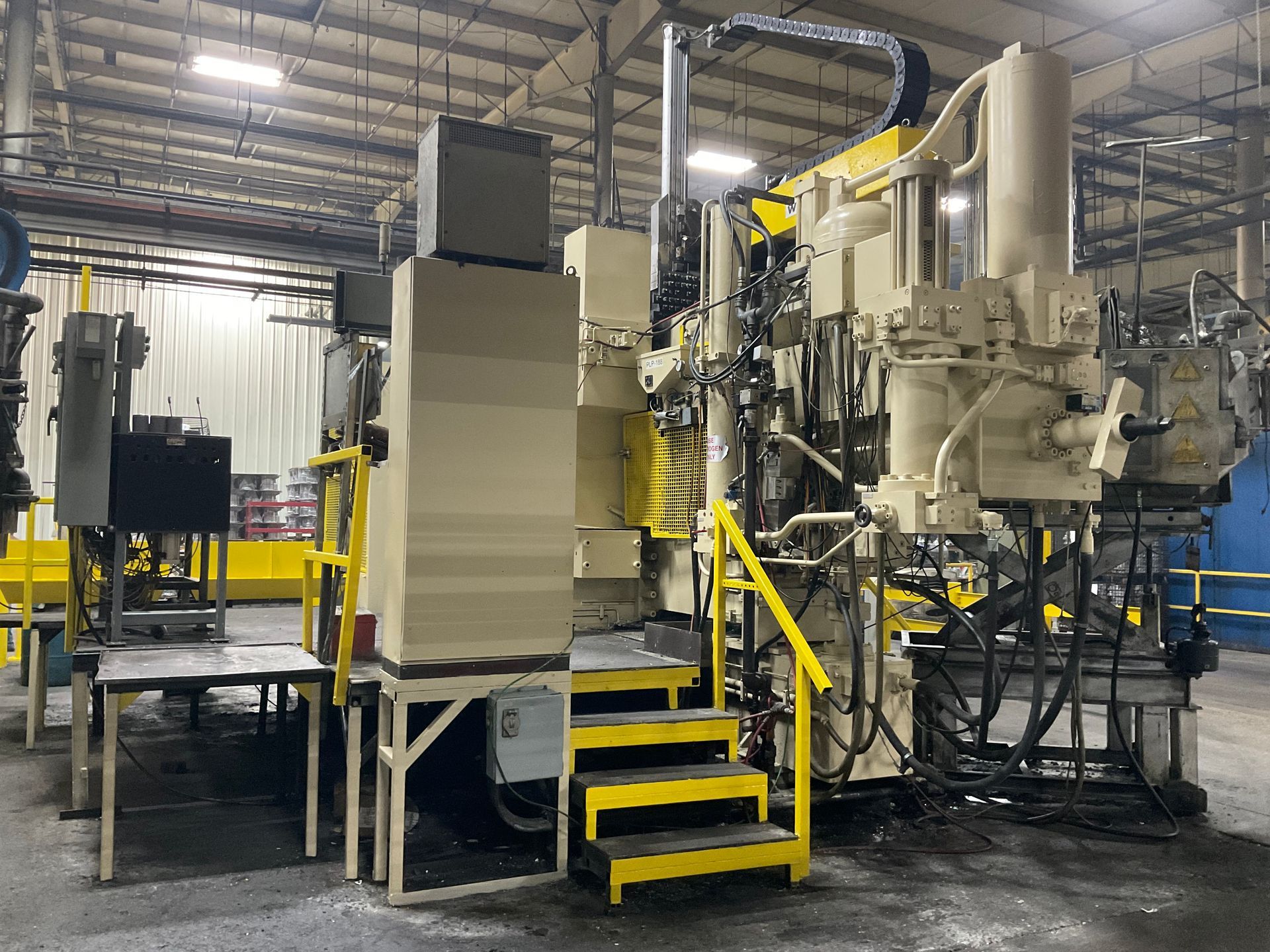 A large machine is sitting in a factory with stairs leading up to it.