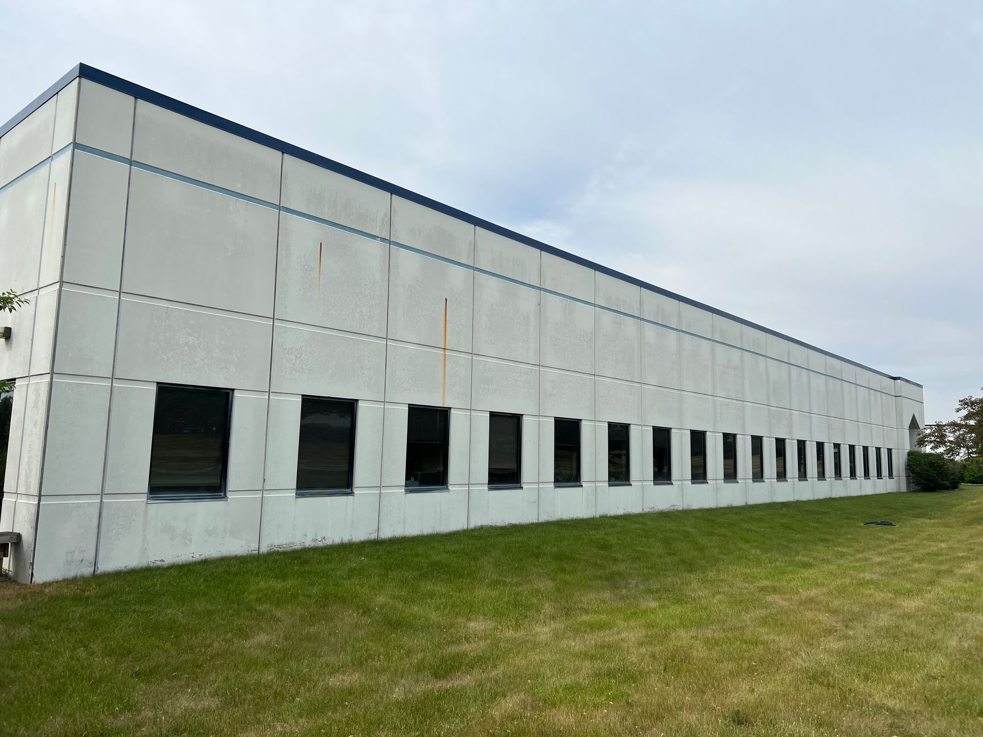A large building with a lot of windows is sitting on top of a lush green field.