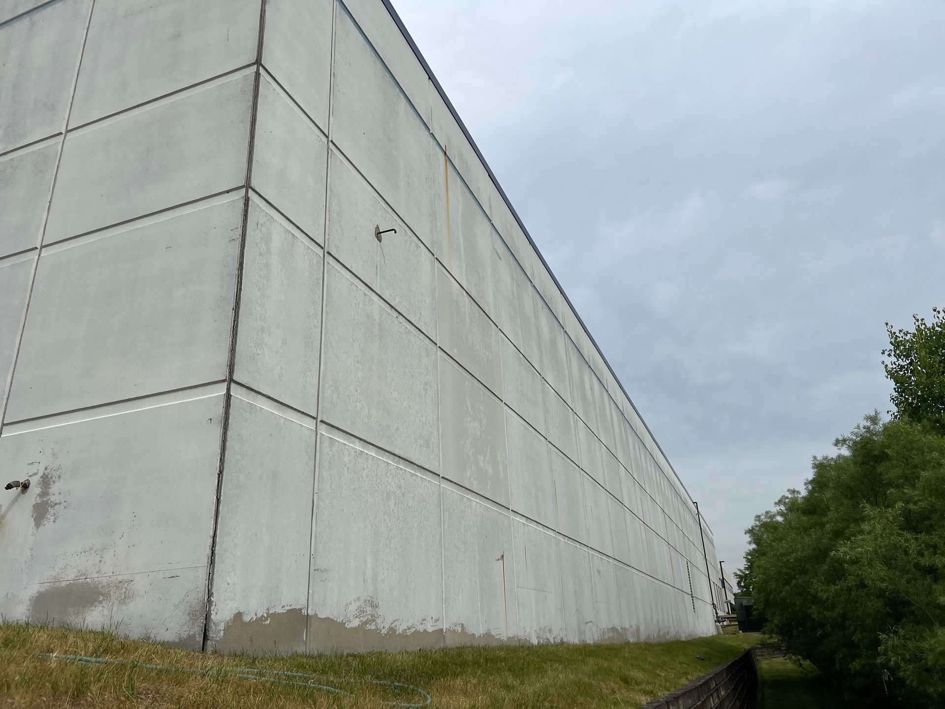 A large white building is sitting on top of a grassy hill.