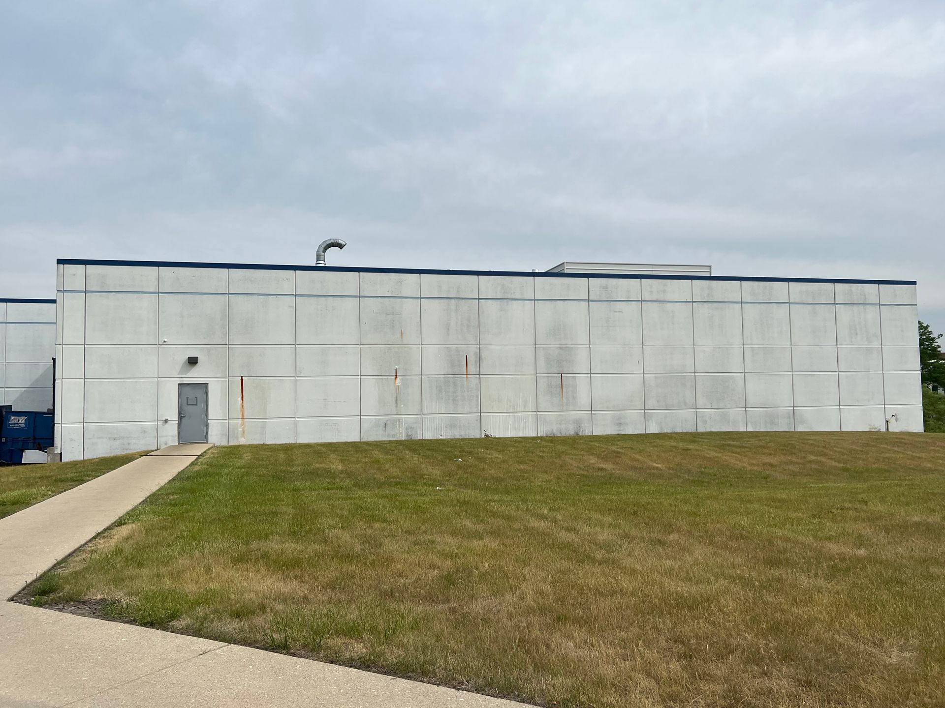 A large concrete building is sitting in the middle of a grassy field.