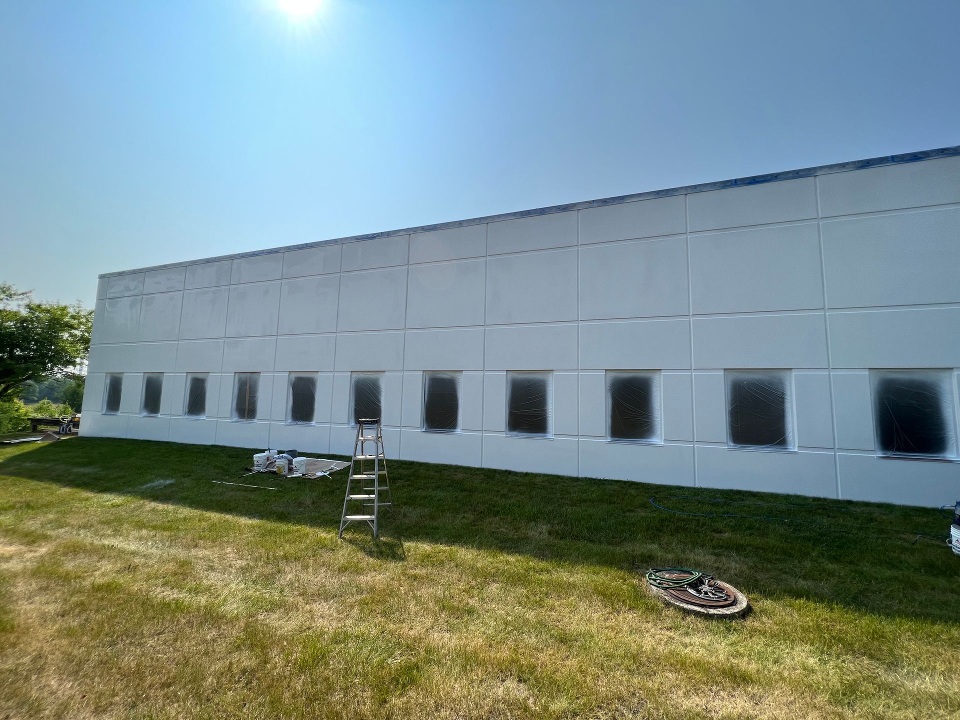 A large white building with a lot of windows is being painted.