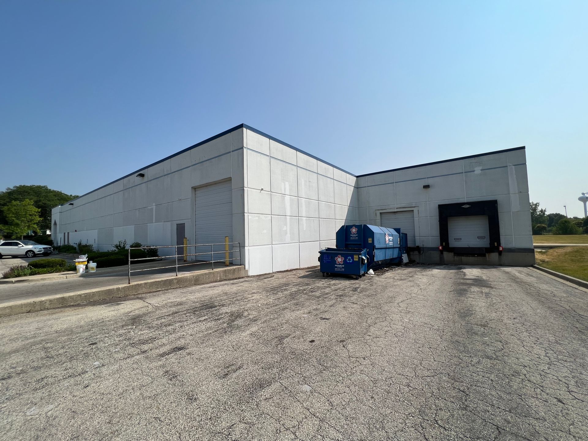 A large white building with a blue dumpster in front of it.
