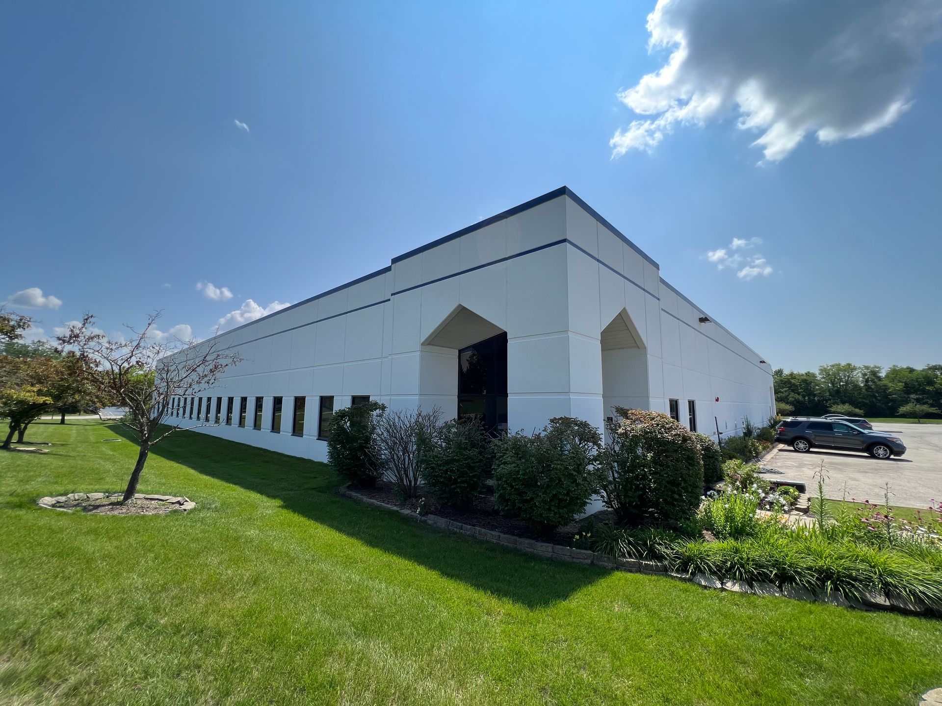 A large white building with a lot of windows is sitting on top of a lush green field.
