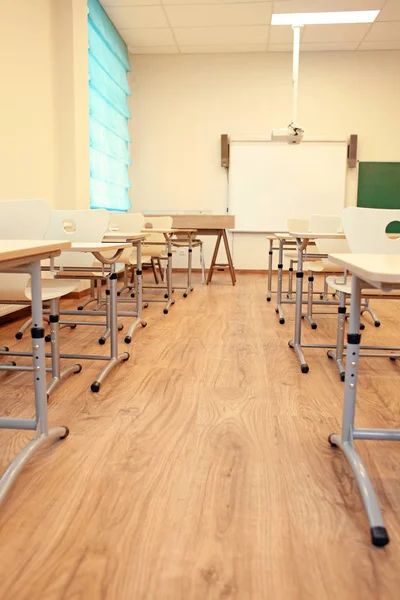 An empty classroom with wooden desks and chairs