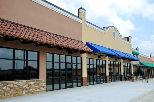 A row of store fronts with blue awnings on them