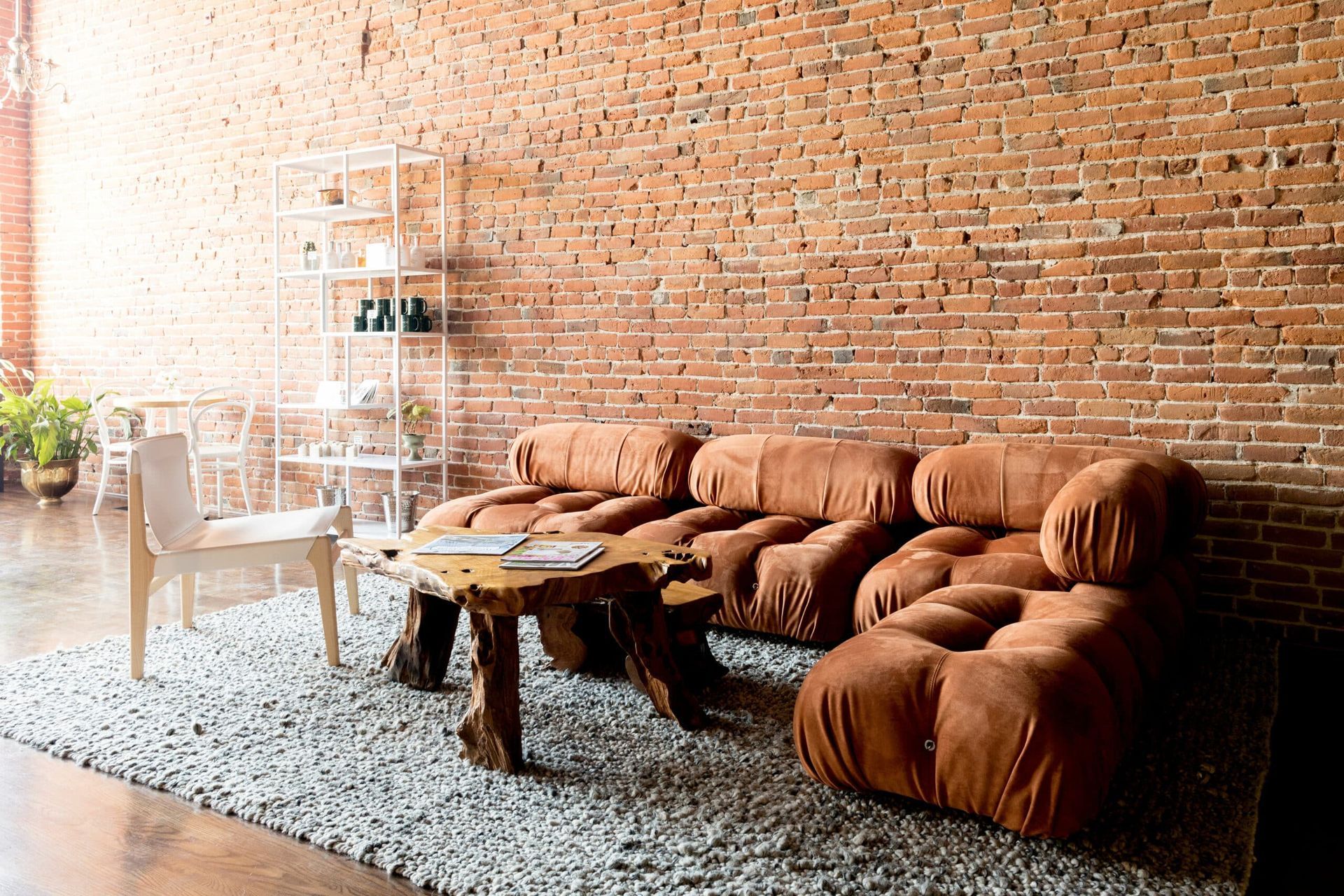 A living room with a brick wall and brown furniture