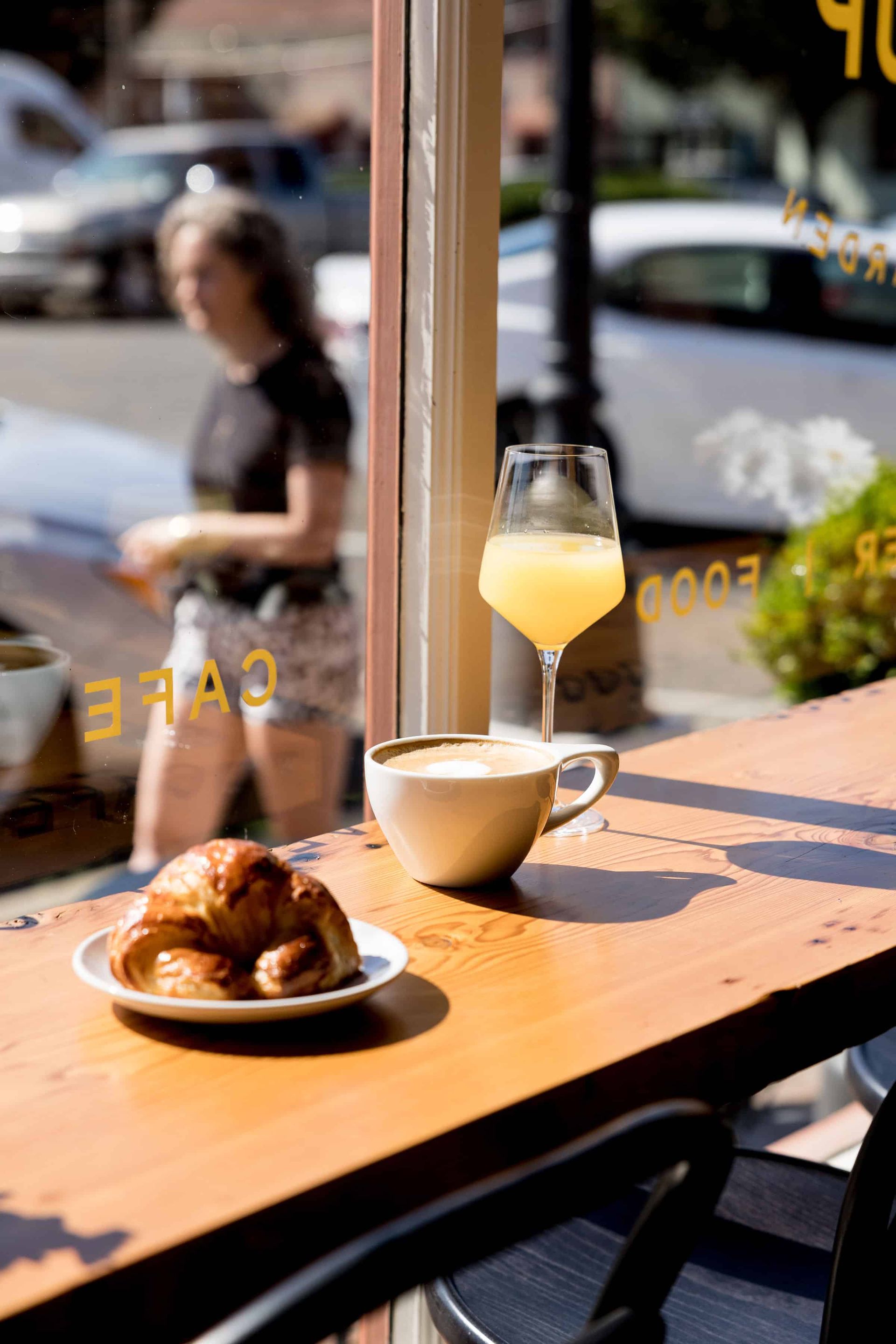 A table with a plate of croissants , a cup of coffee and a glass of orange juice.