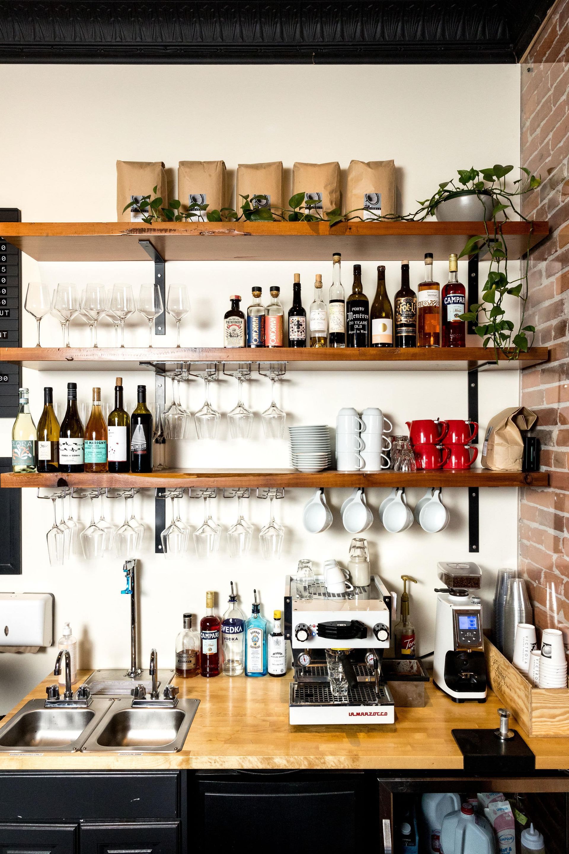 A kitchen with a sink and shelves filled with bottles and glasses.