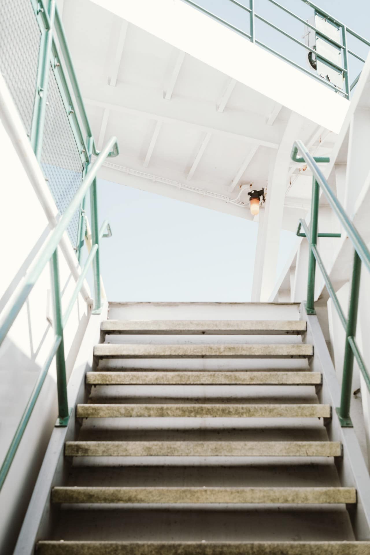 A set of stairs with a green railing leading up to a building.