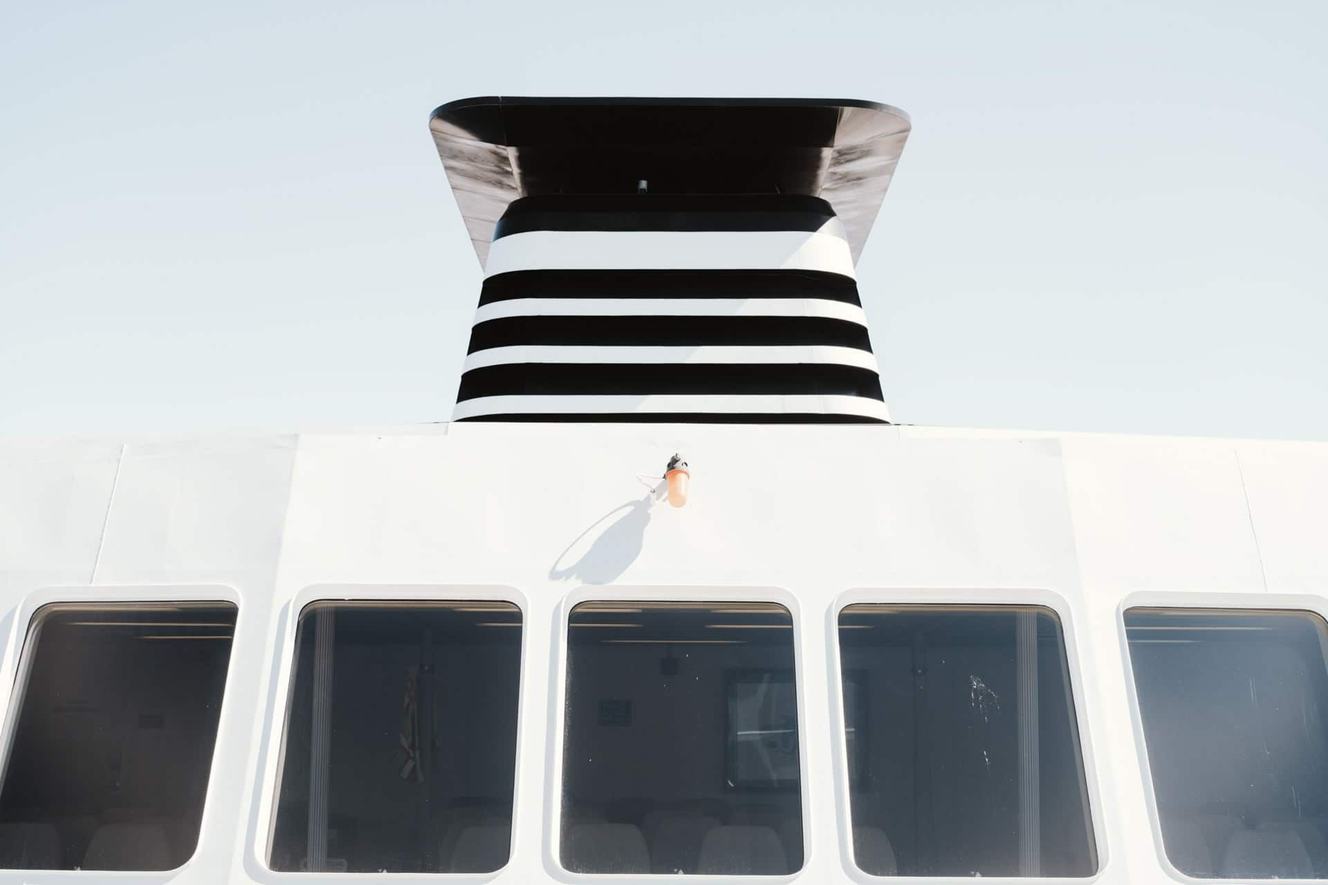 A white boat with a black and white striped exhaust pipe on top of it.