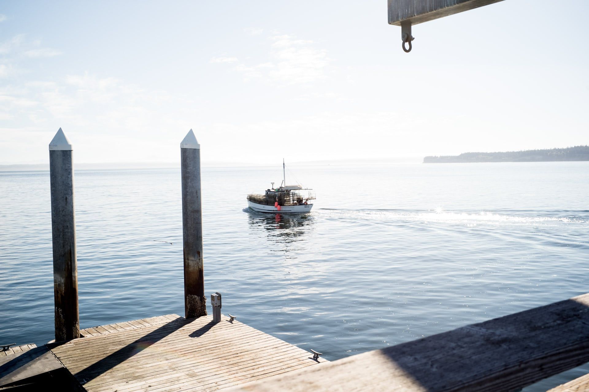 A boat is floating on top of a body of water next to a dock.