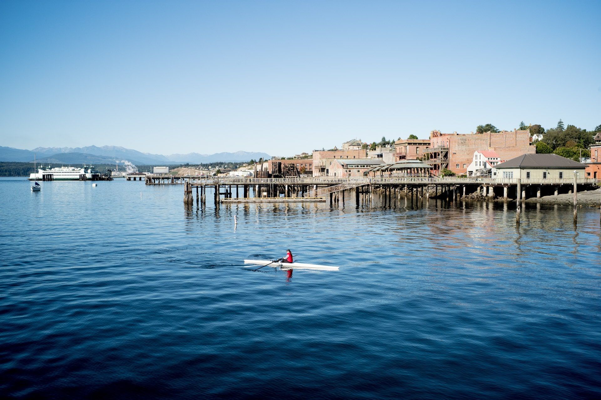 A person is paddling a kayak in the water near a dock.