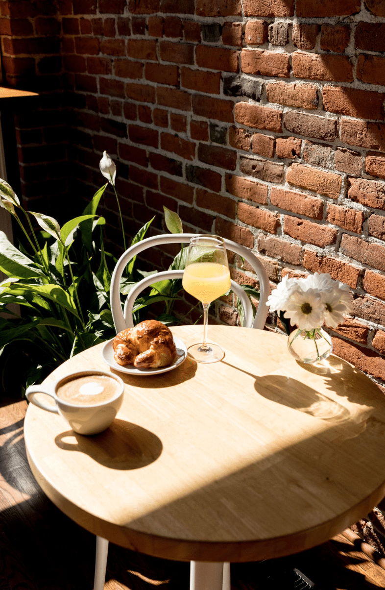 A table with a cup of coffee , croissants , and a glass of orange juice.