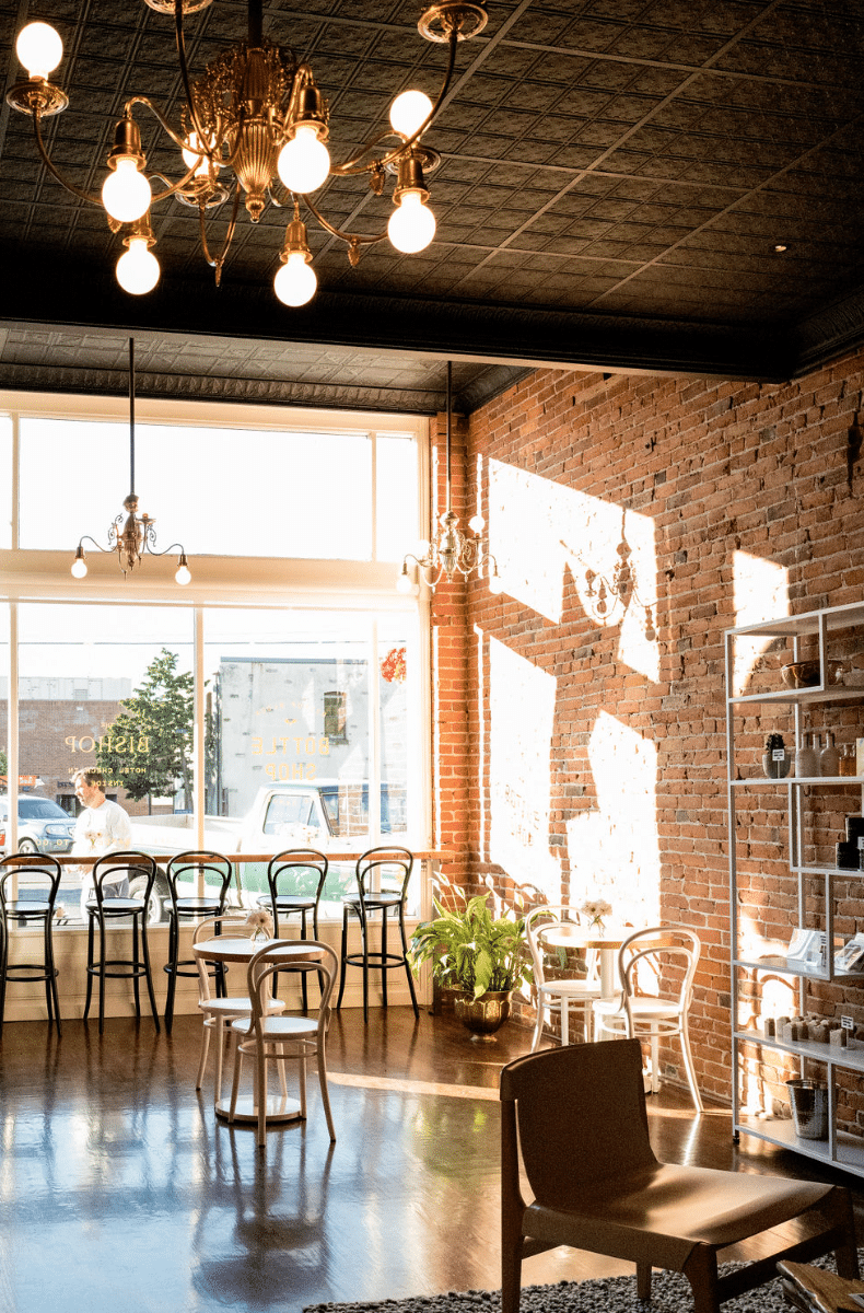 A restaurant with tables and chairs and a chandelier hanging from the ceiling.