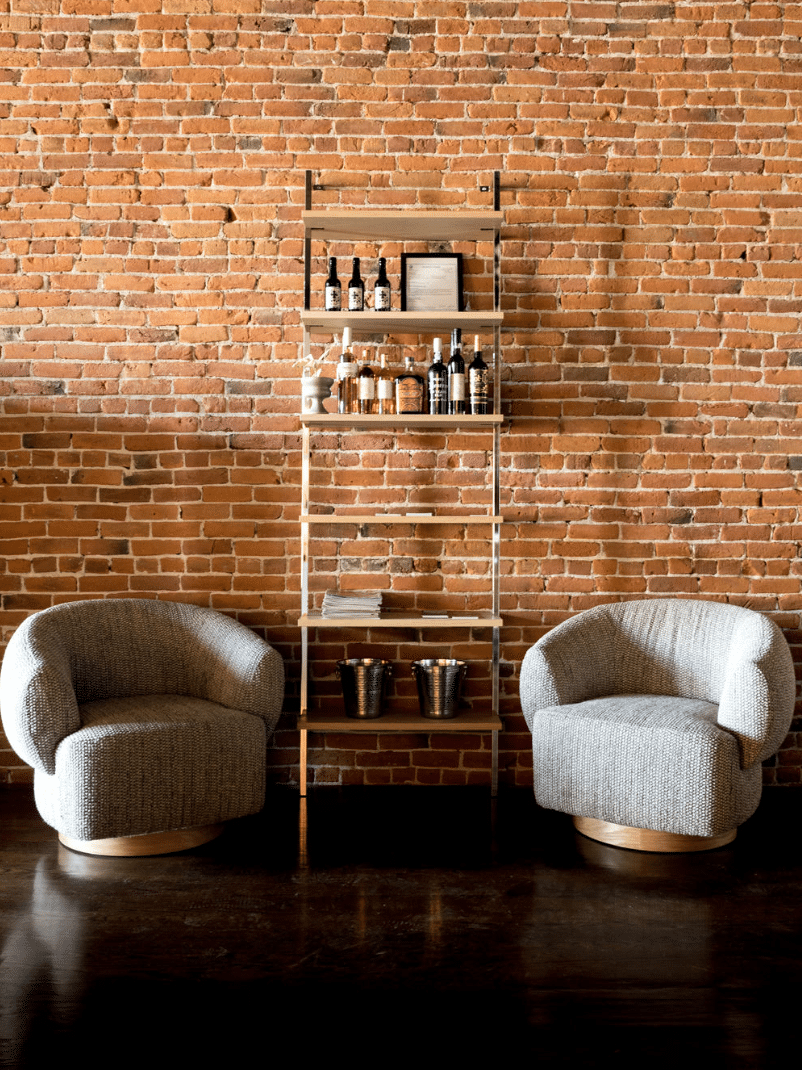 Two chairs are sitting in front of a brick wall.