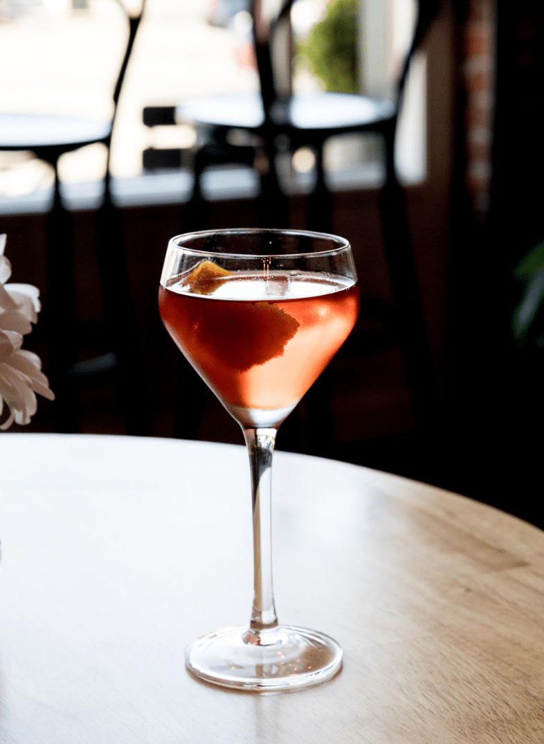 A glass of wine is sitting on a wooden table.