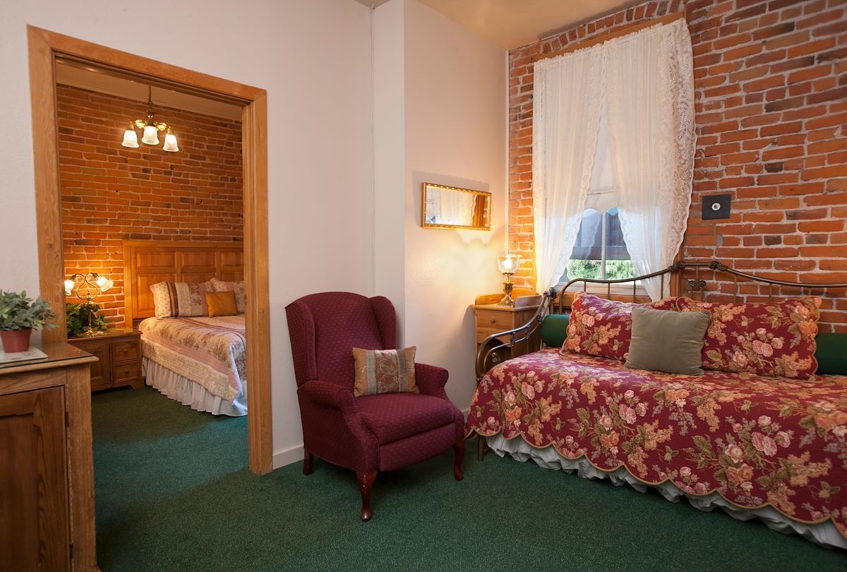 A bedroom with a brick wall , a couch , a chair and a bed.