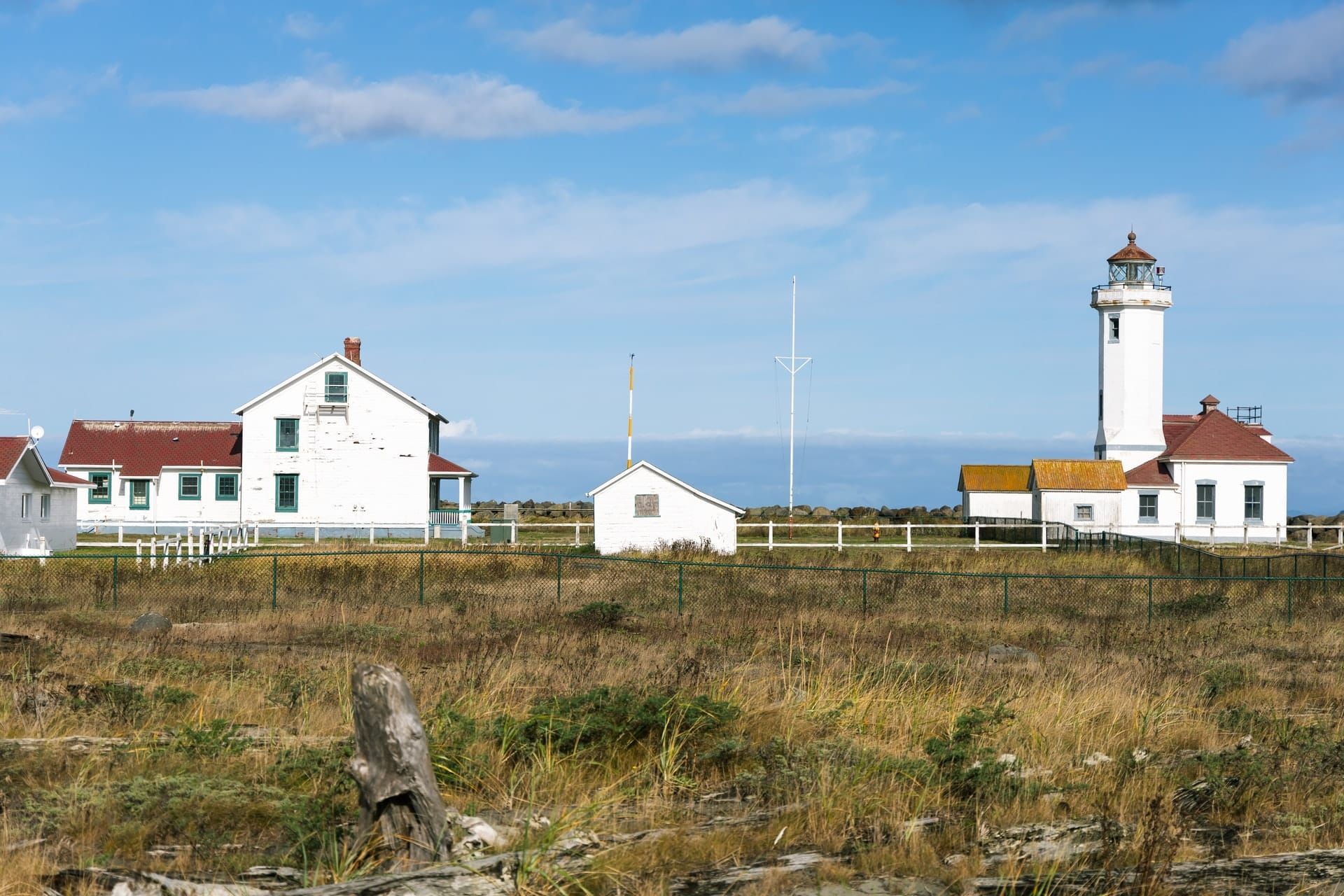 A lighthouse sits in the middle of a grassy field