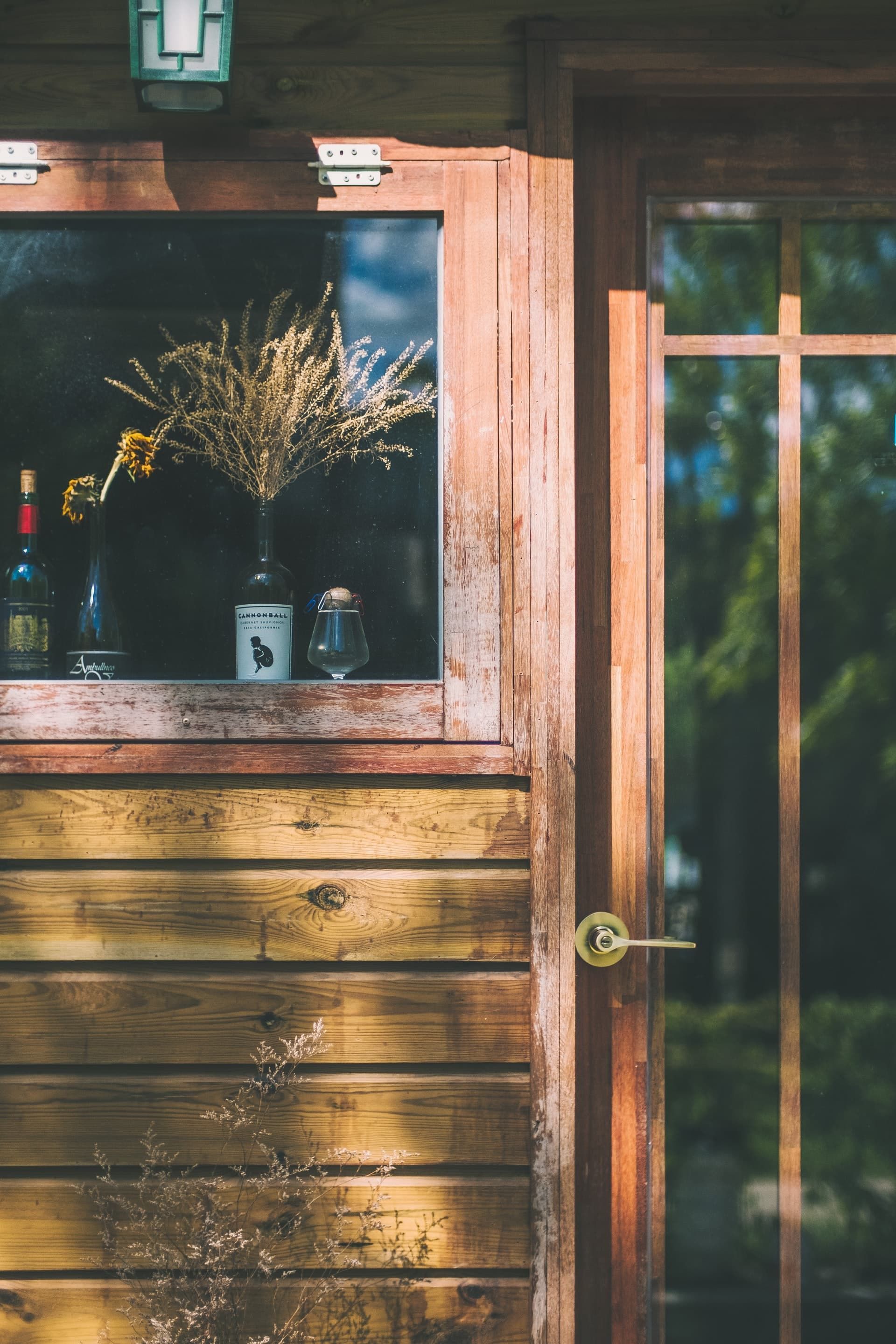 A wooden door with a window and a vase of flowers on it.