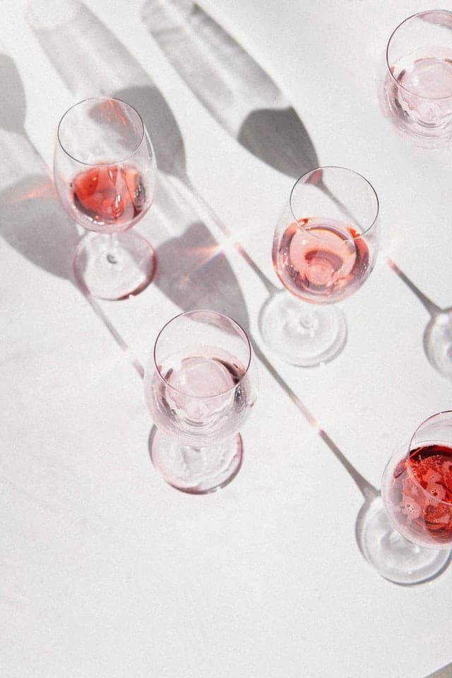 A group of wine glasses filled with pink wine on a table.