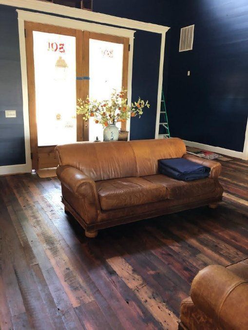 A living room with a brown leather couch and a blue wall