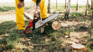 A man wearing a hard hat and goggles is measuring a wall with a level.