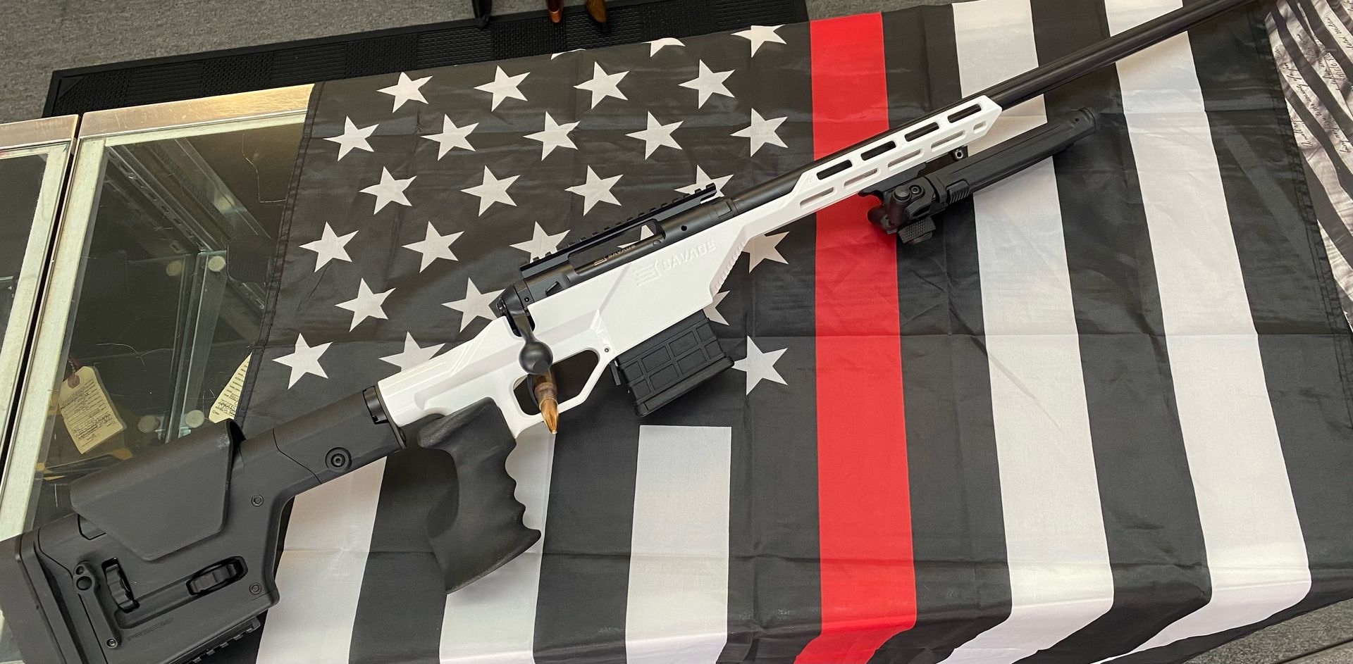 A white and black rifle laying on a black and white American flag with a red stripe.