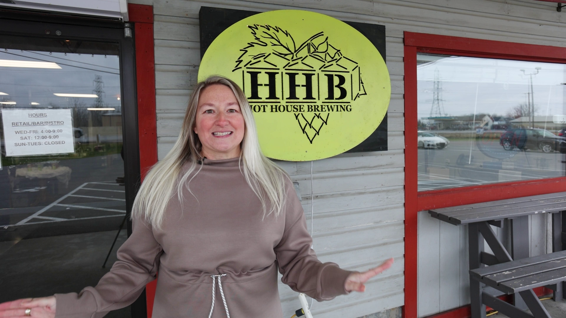 Kim Antenucci is standing in front of a building with a sign that says hhb on it.