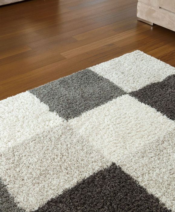 A black and white checkered rug on a wooden floor