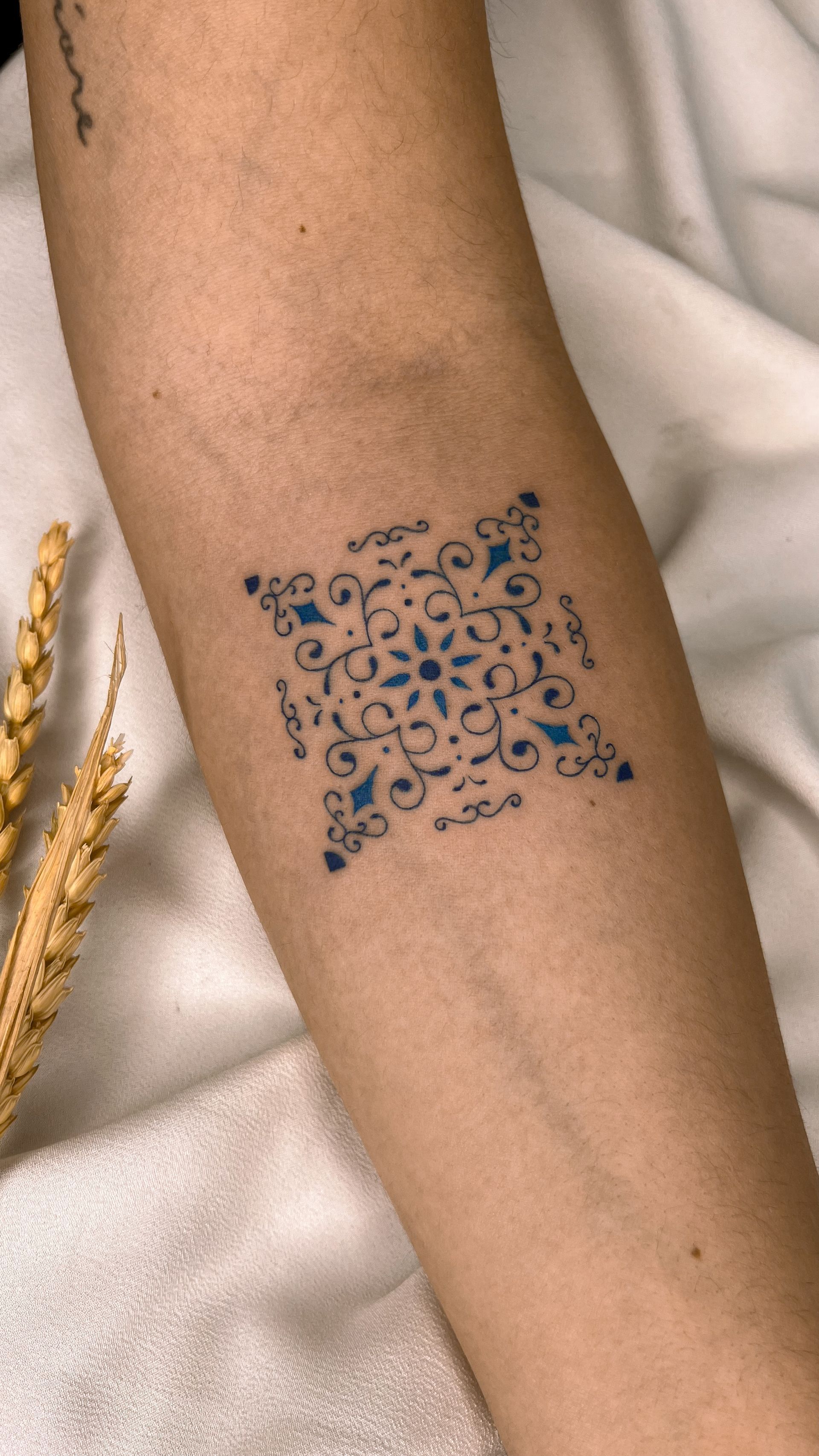 Uma mulher tem uma pequena tatuagem azul no antebraço.