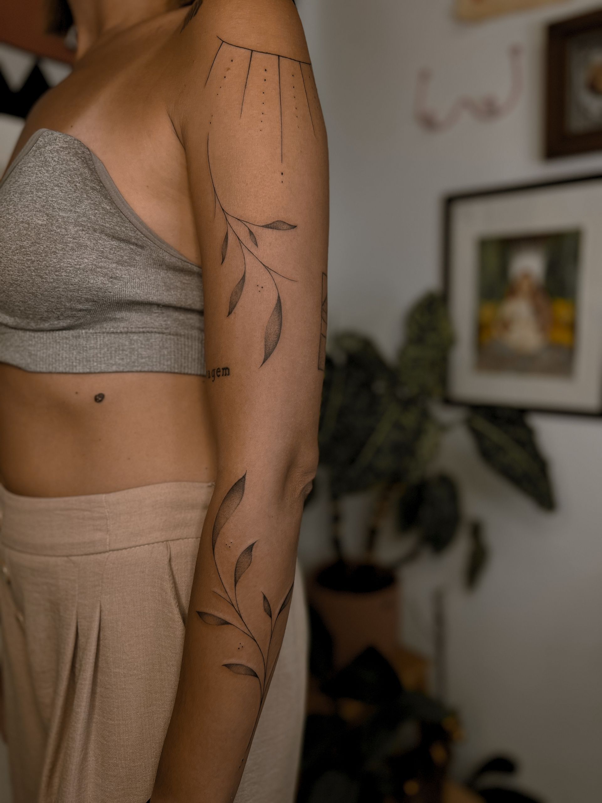 Uma mulher está parada em uma sala com uma tatuagem no braço.