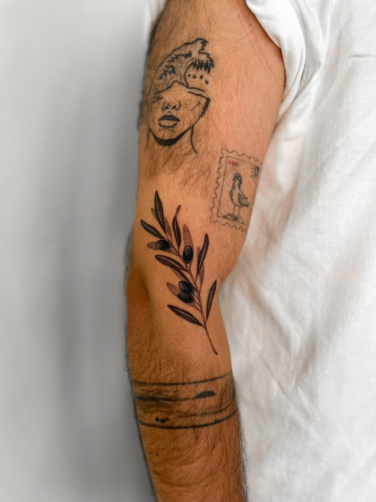 Um homem tem uma tatuagem de um rosto e um galho no braço.