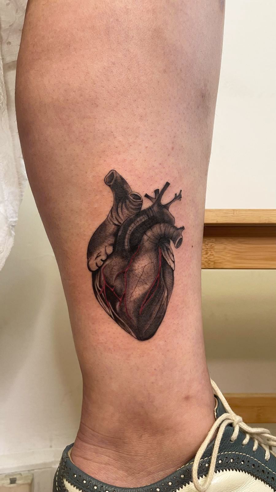 Uma pessoa tem uma tatuagem de um coração na perna.
