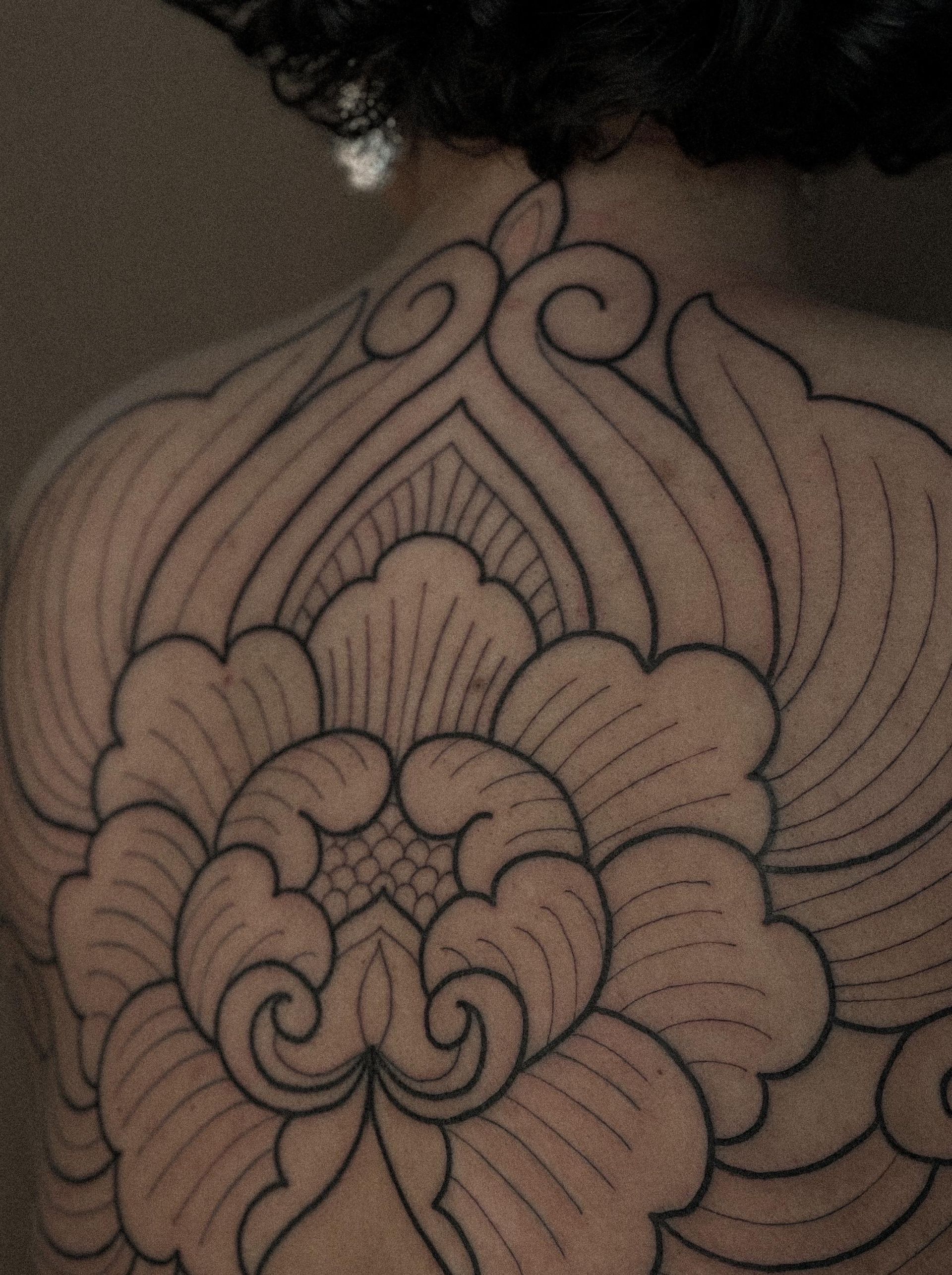Uma mulher tem uma tatuagem de uma flor nas costas