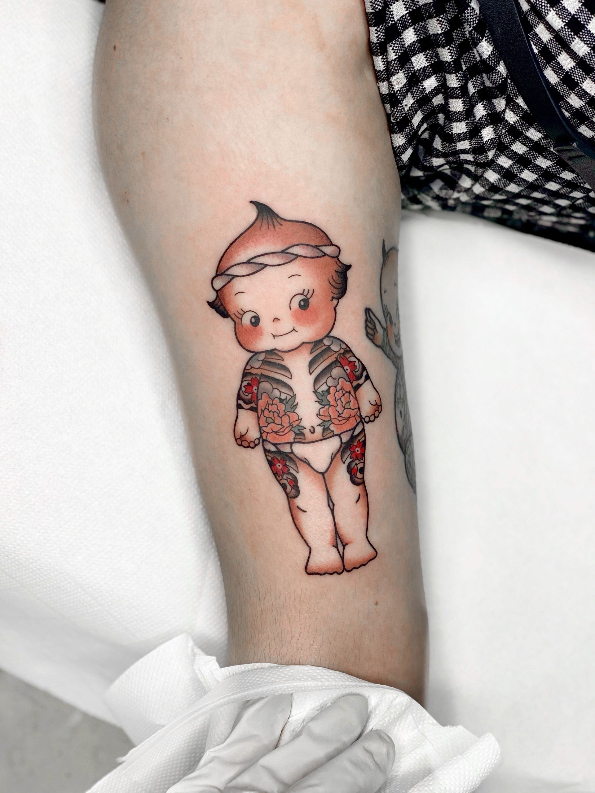 Uma pessoa tem uma tatuagem de uma boneca no braço