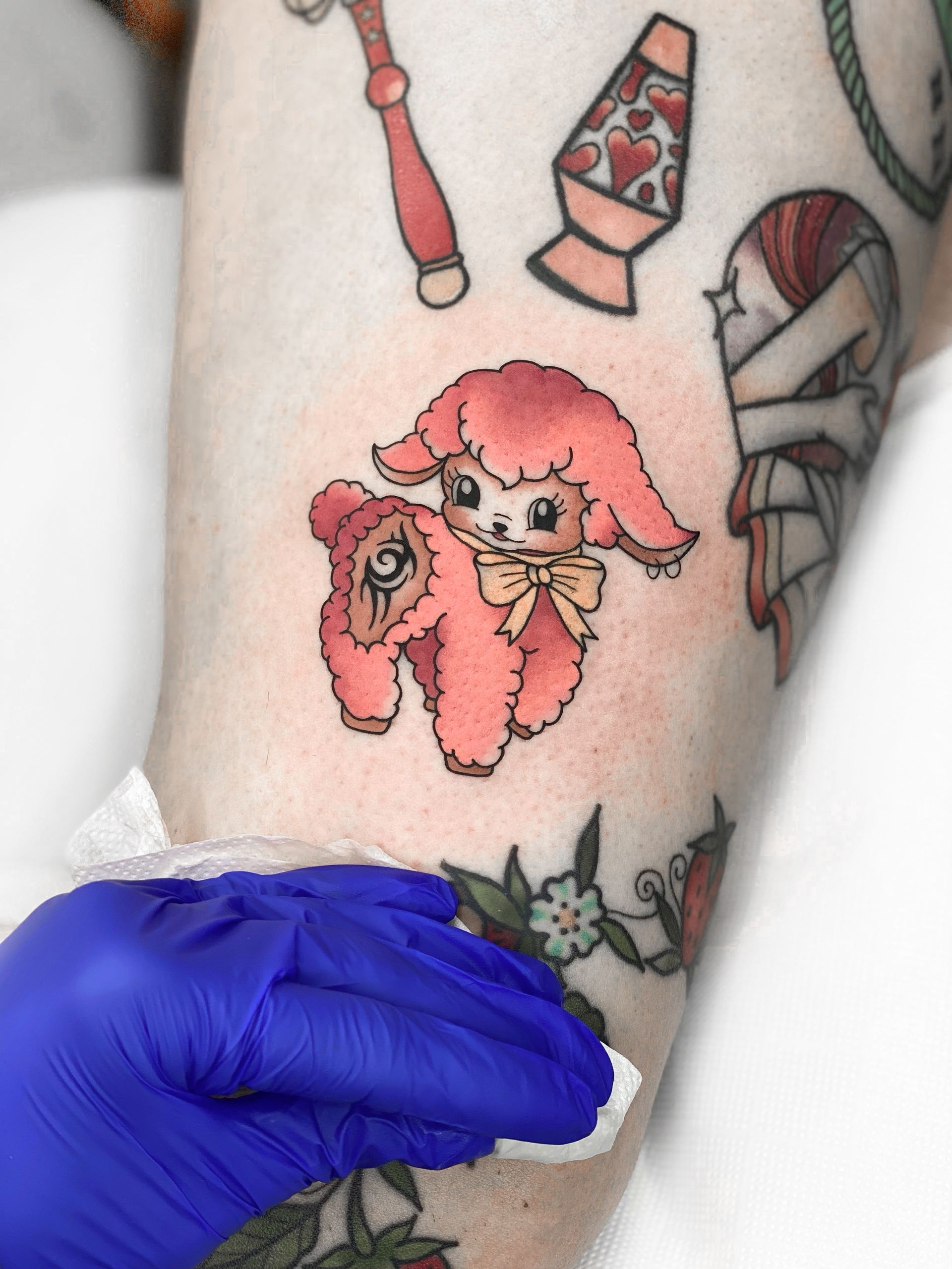 Uma pessoa tem uma tatuagem de um poodle rosa no braço