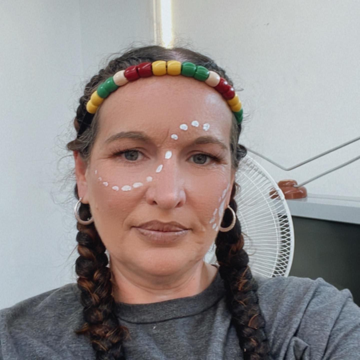 Woman with face paint and braids, wearing a beaded headband.