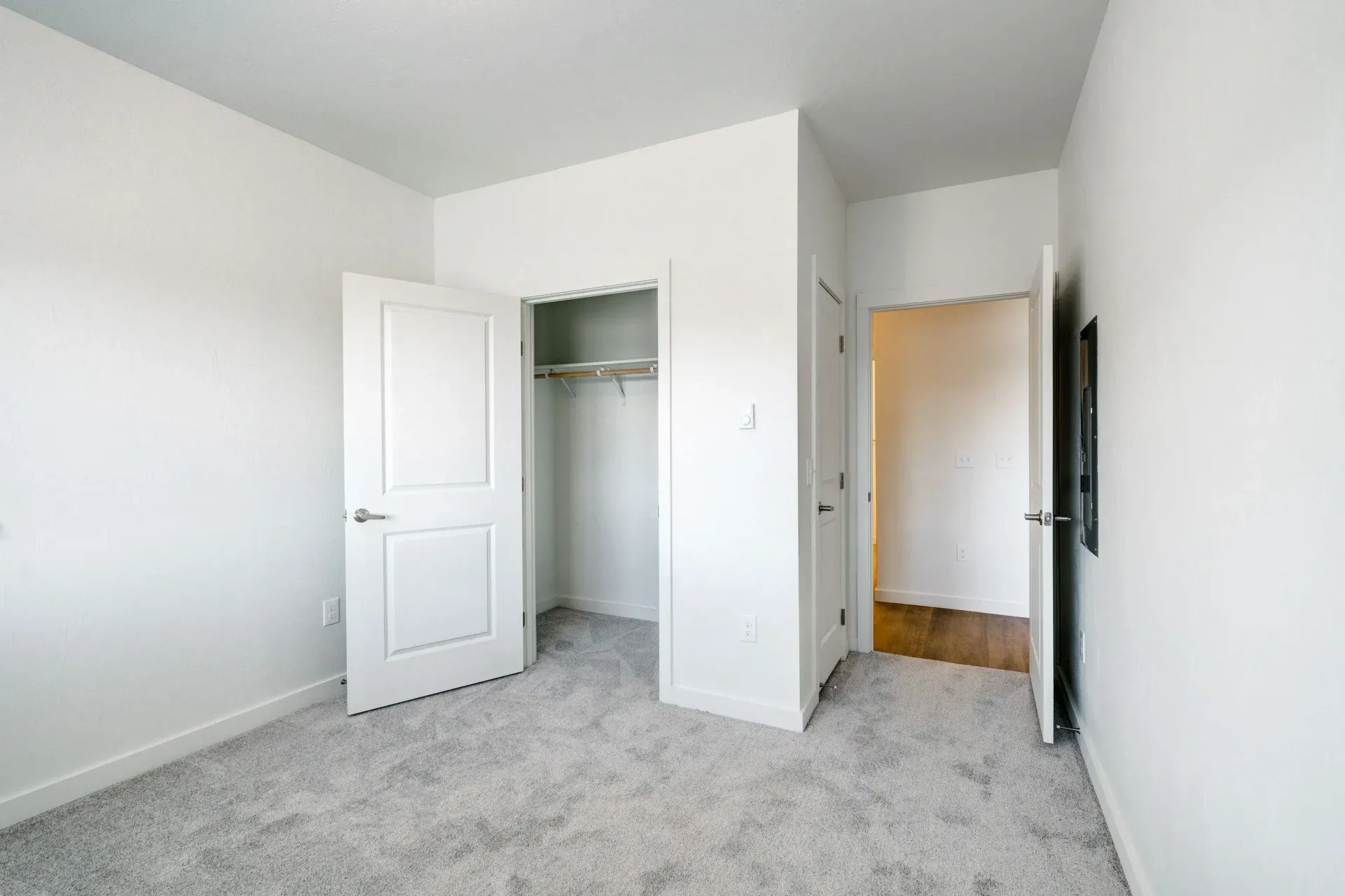 Unfurnished bedroom with open closet, neutral walls, and light carpeting.