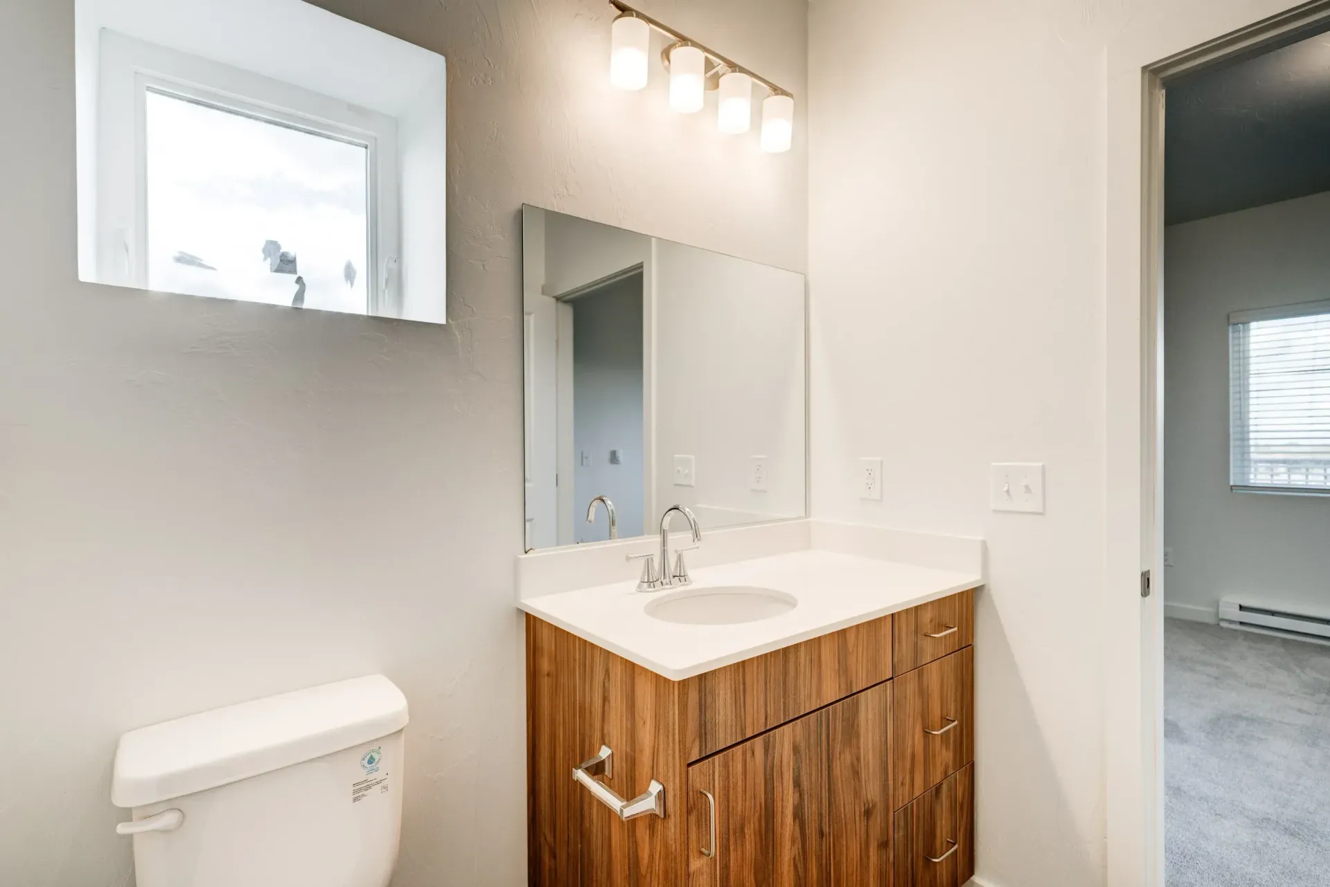 Bathroom featuring a vanity with sink, mirror, toilet, and window.