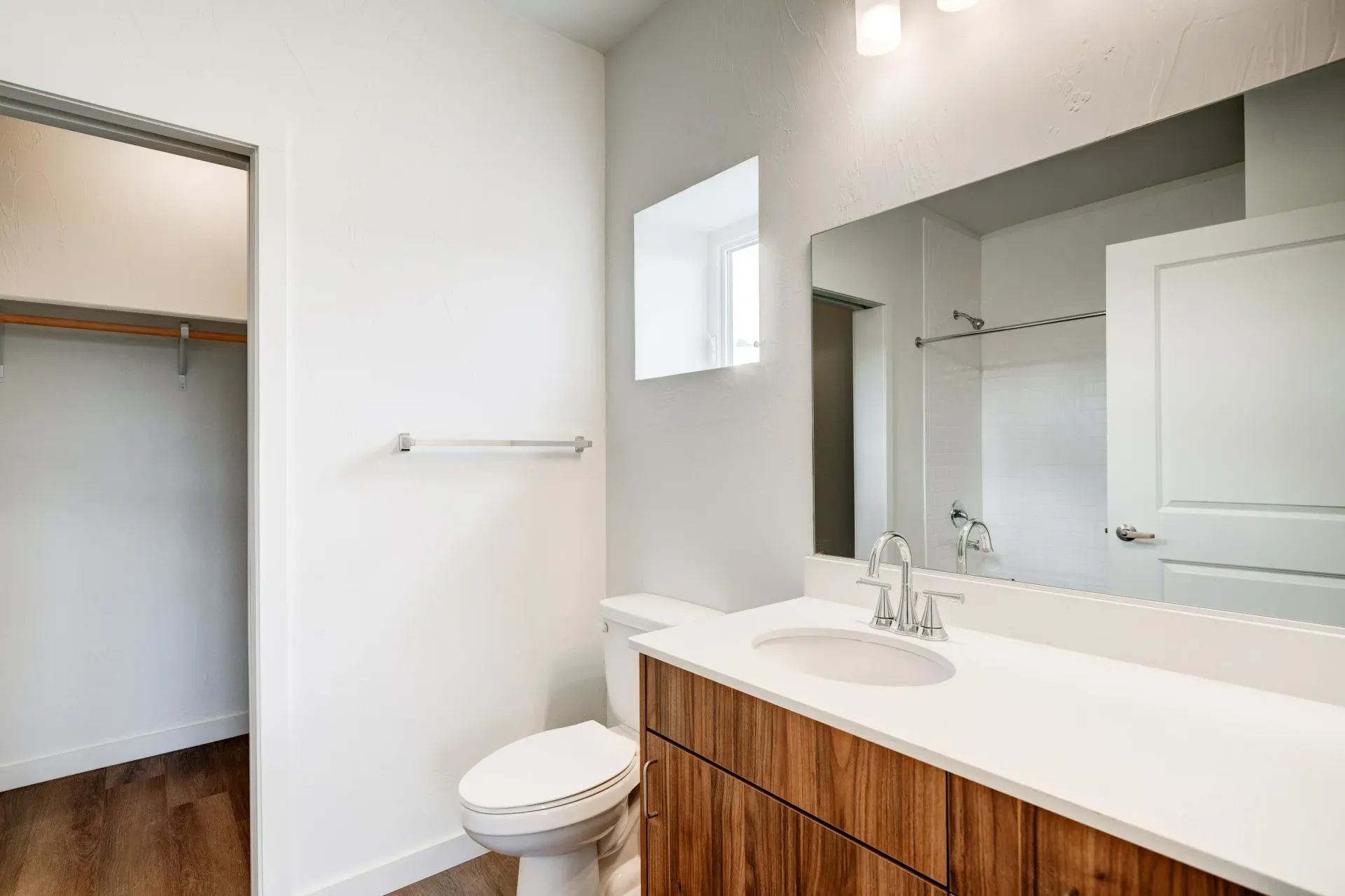 Bathroom inside an apartment with a white countertop, sink, toilet, and shower.