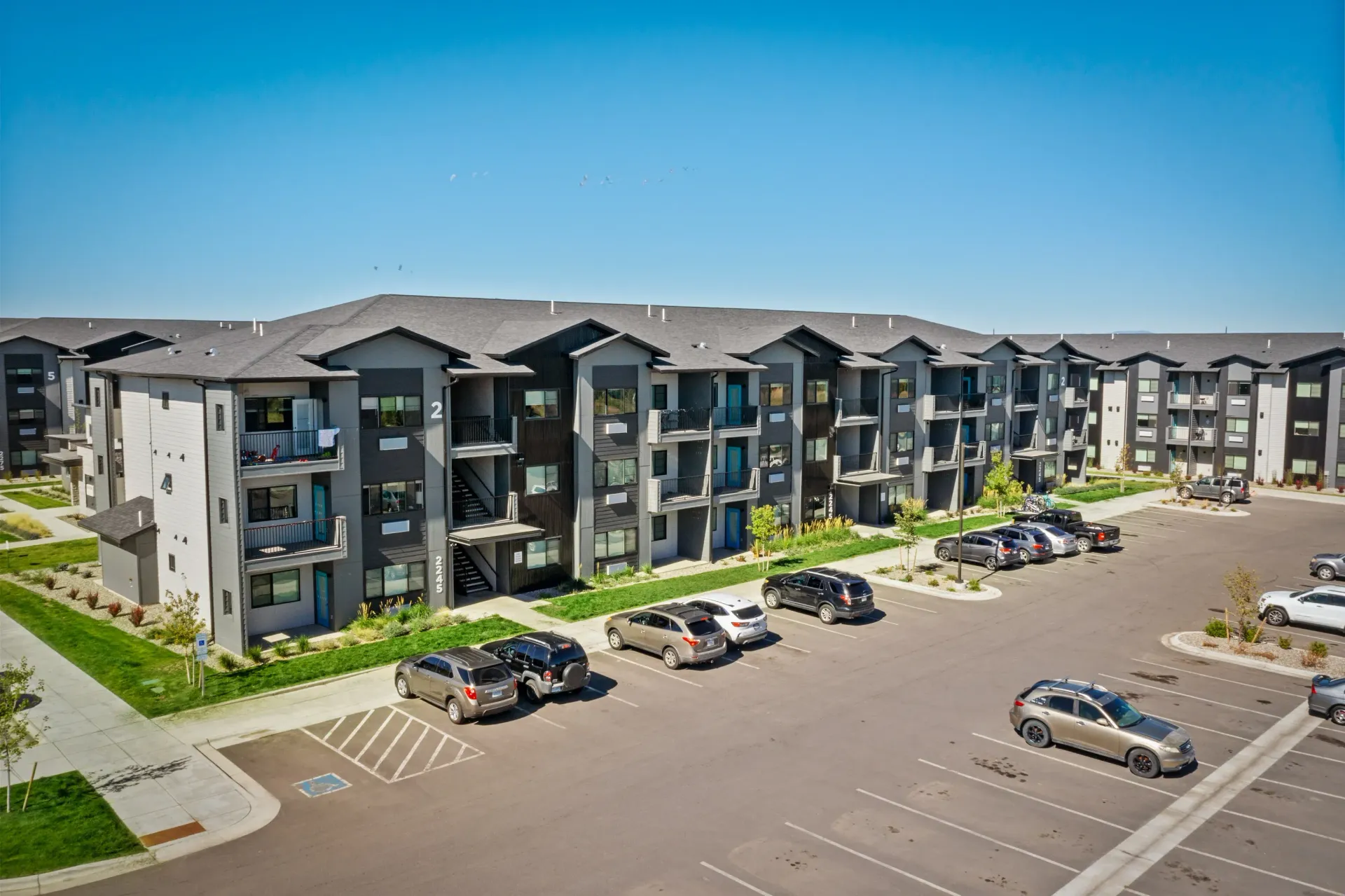 Aerial view of a modern apartment complex with multiple buildings and a large parking lot.