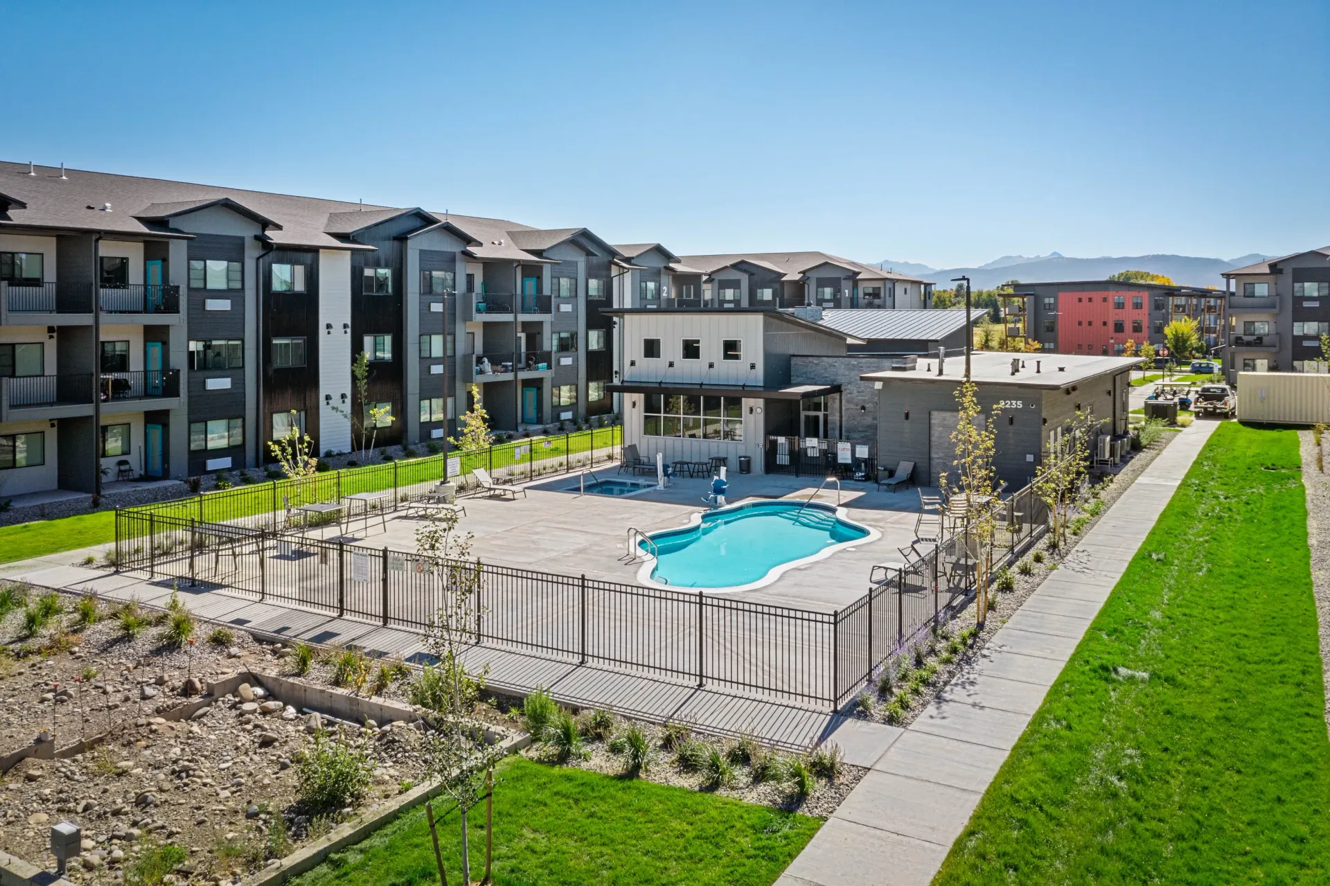 Aerial view of a modern apartment community with a central pool and surrounding buildings.