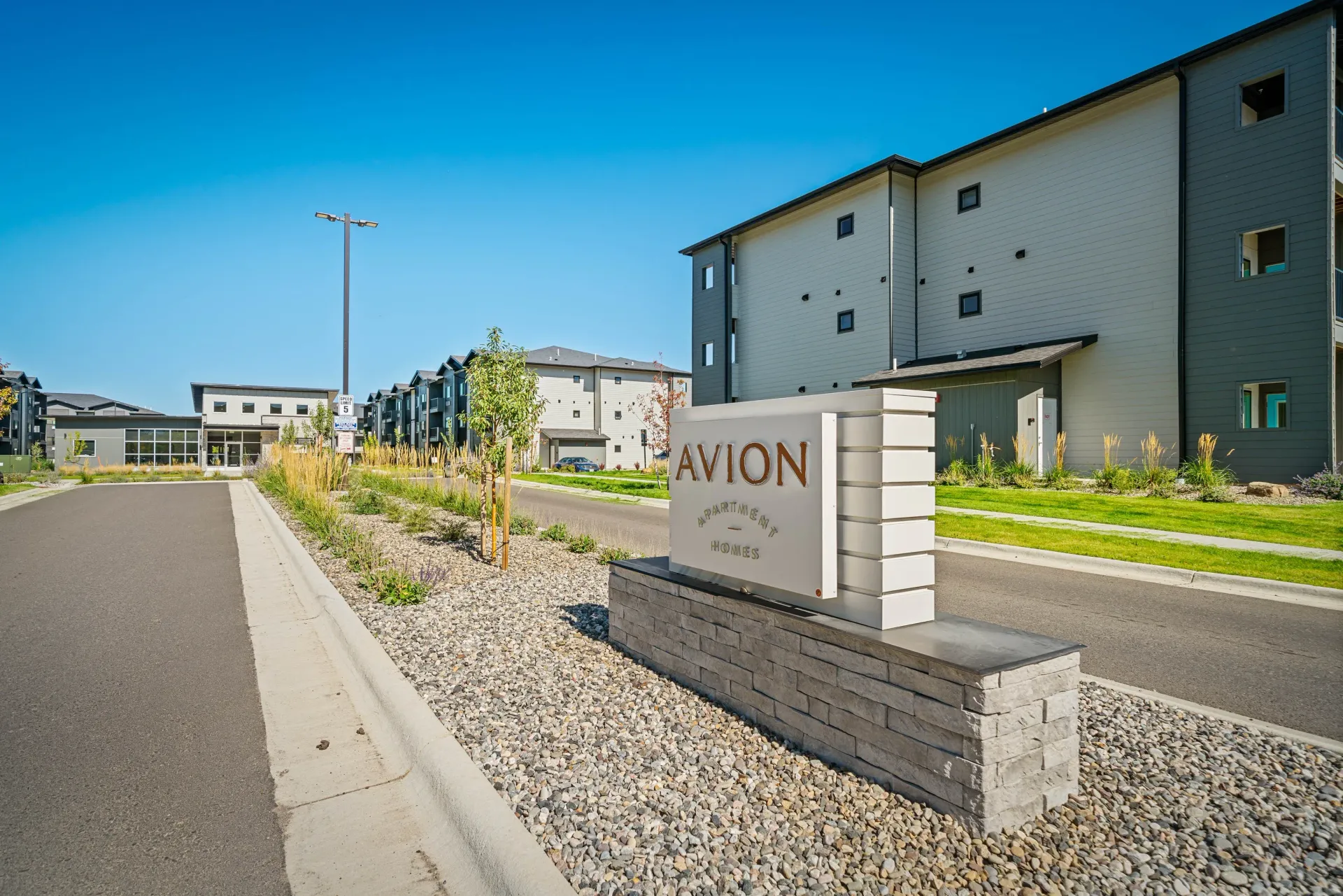 Exterior view of Avion Apartments community entrance with modern buildings and landscaping.