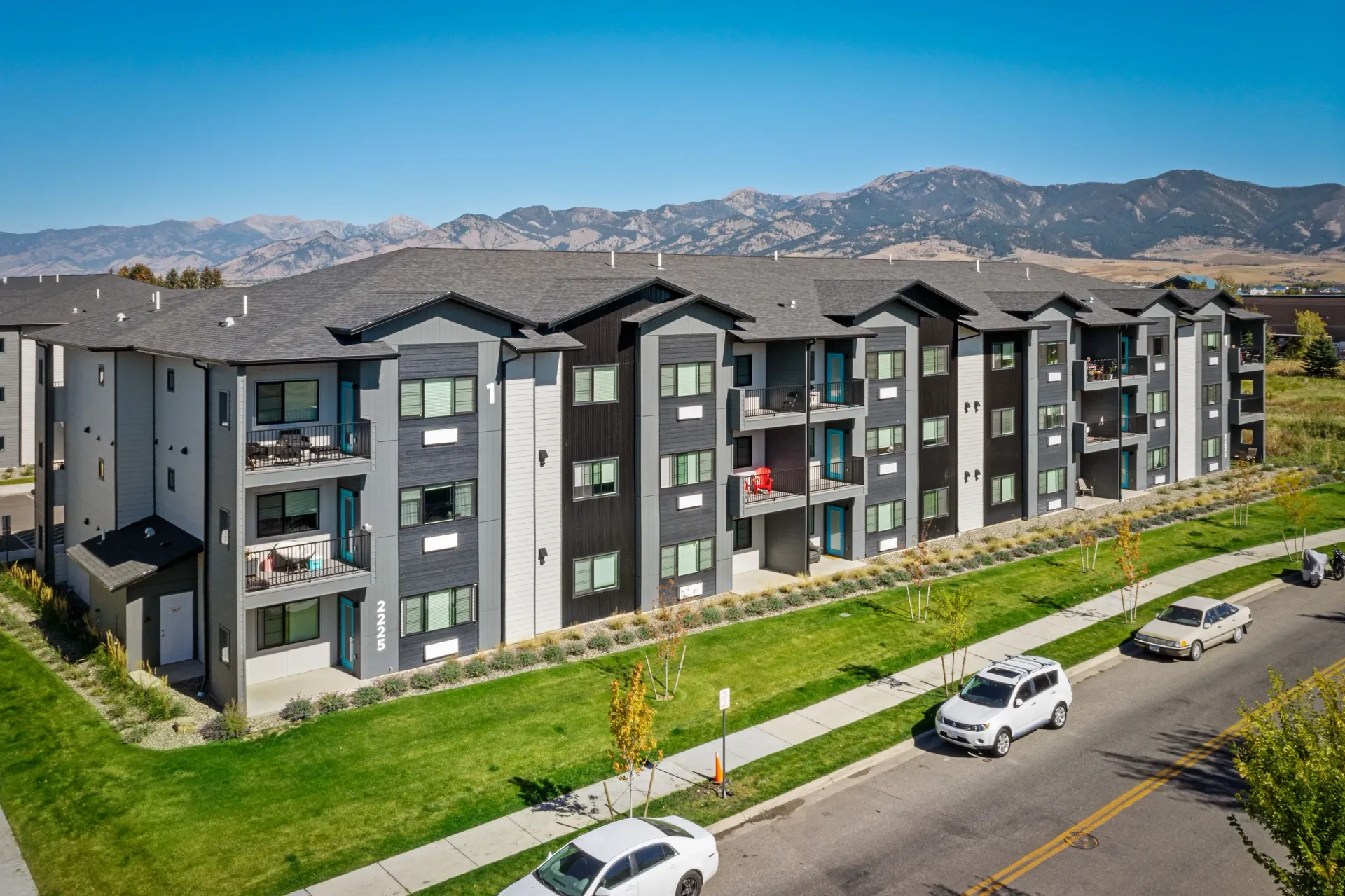 Aerial view of a modern apartment community with multi-story buildings, balconies, and manicured lawns.