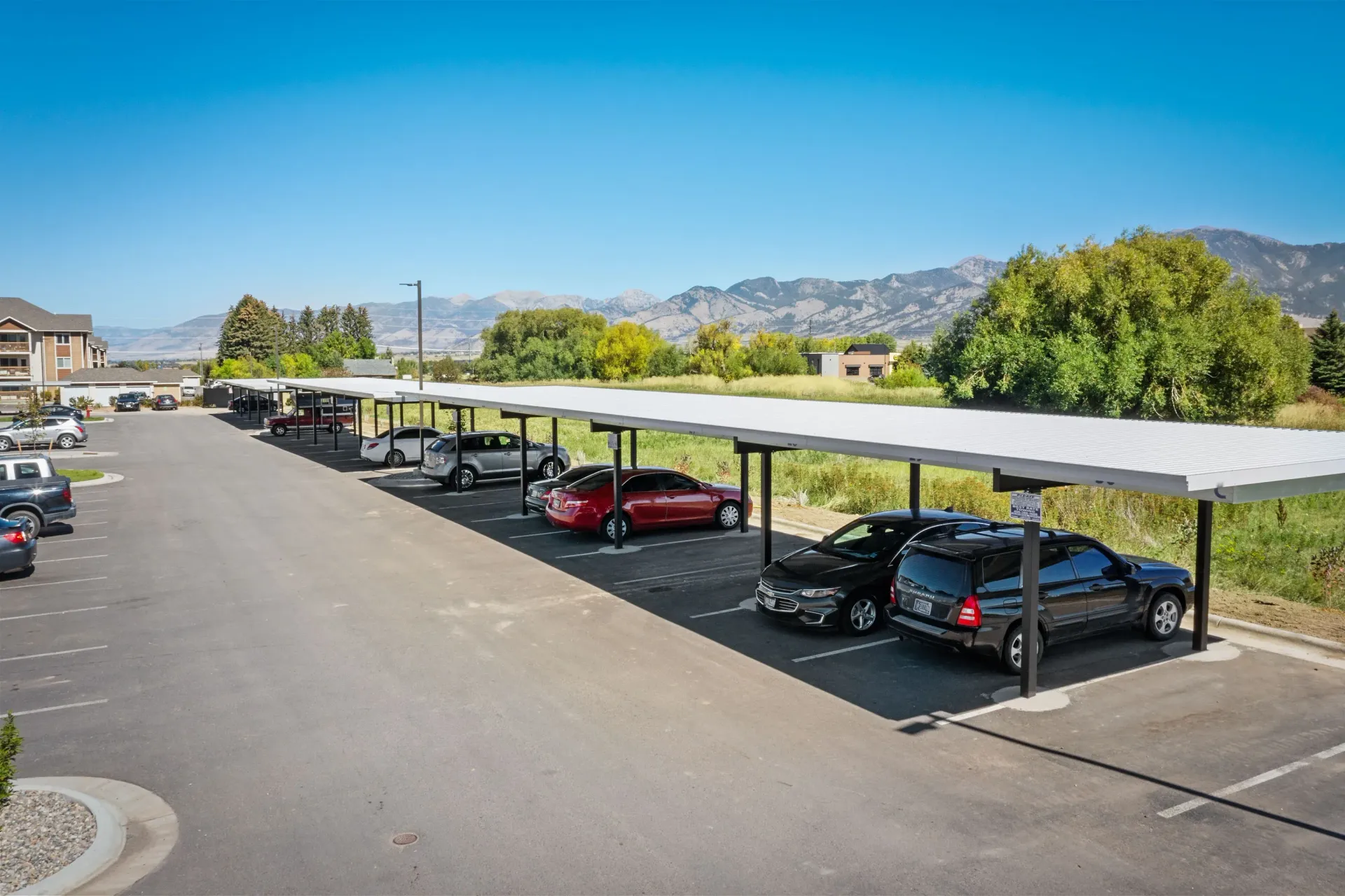 Exterior parking lot with covered carports and a mountain backdrop.