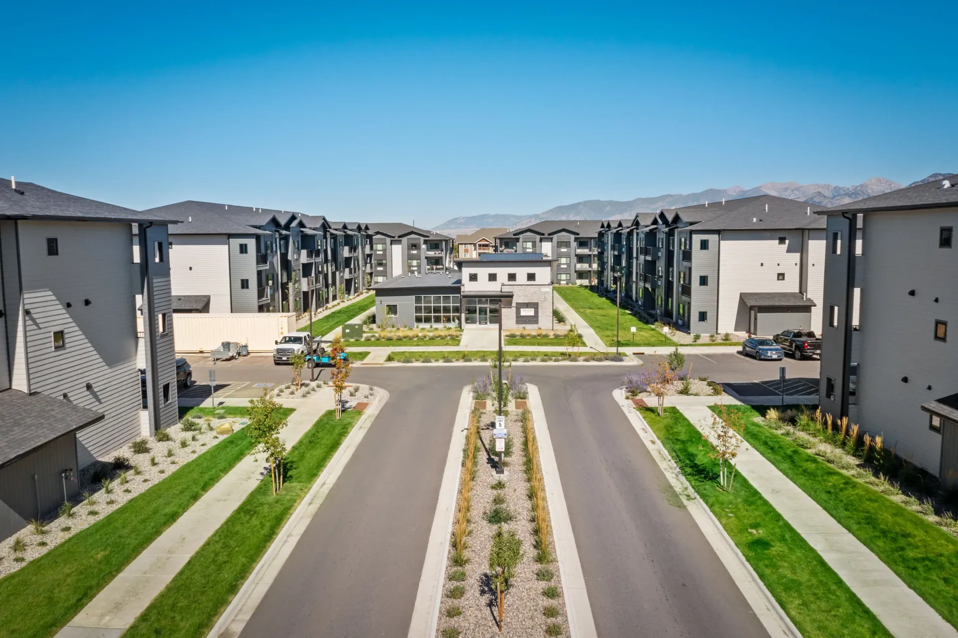 Aerial view of a modern apartment community with green lawns and central driveways.