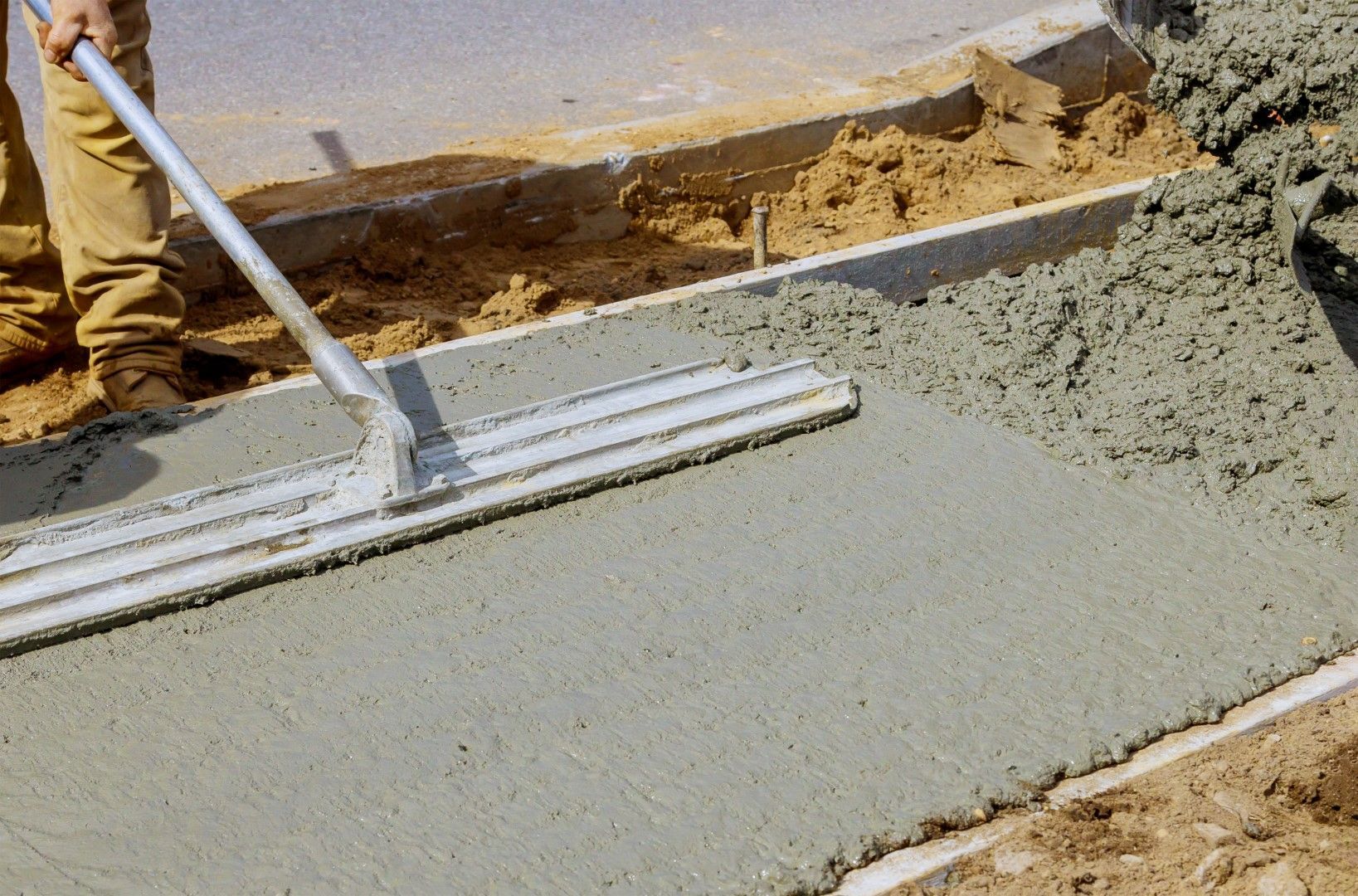 A person is spreading concrete with a trowel.