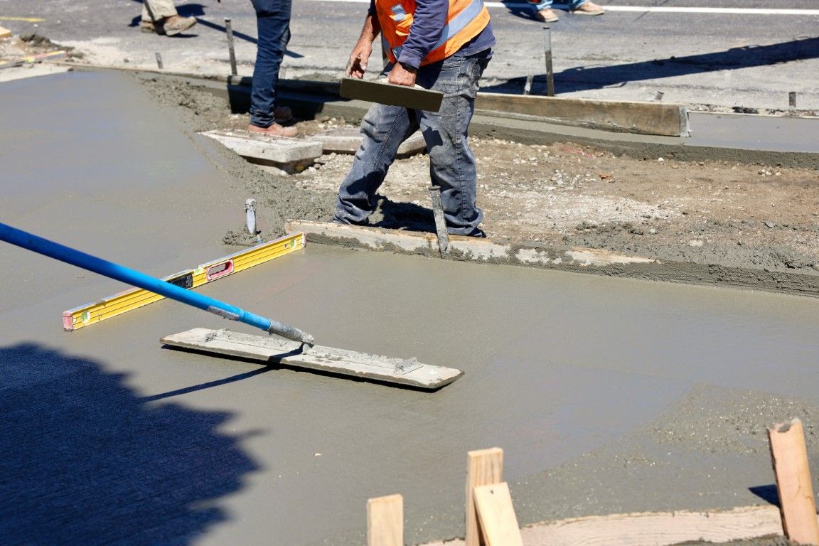 A man is leveling a concrete surface with a level.