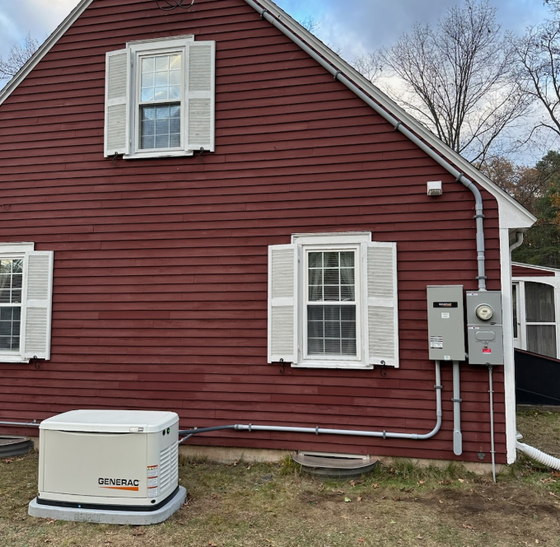 A red house with white shutters and a generator in front of it.